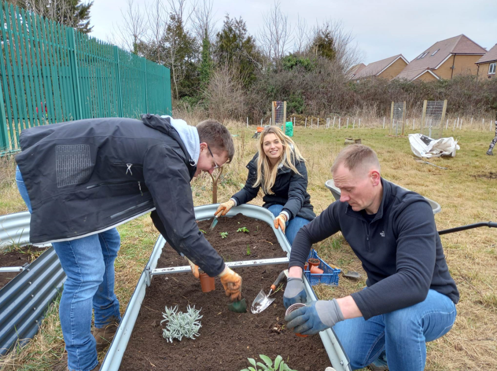 Three volunteers planting troughs at One Lockleaze Sports Centre
