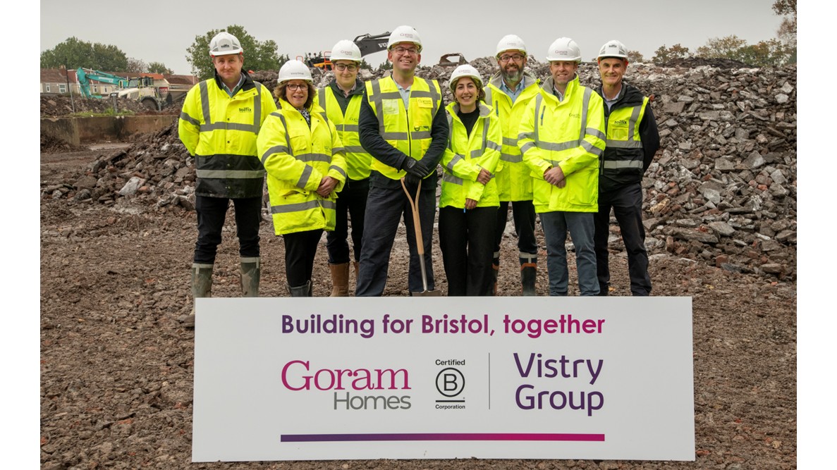 Members of Goram Homes and Vistry teams with Cllr Barry Parsons. They're standing on a construction site in front of soil pile. A branded sign is in front of the group, with the caption "Building for Bristol, together"